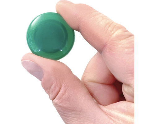 Grüner Glasstein wird in der Hand gehalten.