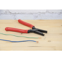 Abisolierzange mit elektrischen Kabeln auf einem Holztisch