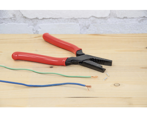 Abisolierzange mit elektrischen Kabeln auf einem Holztisch