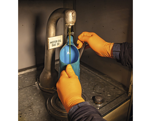 Ein Mann gießt Motoröl SAE 30 in einen blauen Behälter.