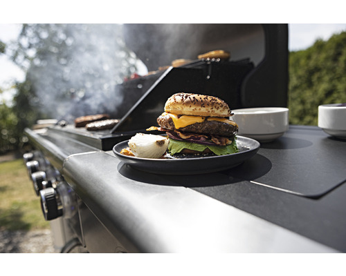 Ein Teller mit einem Burger und einer gegrillten Zwiebel auf einem Grill.