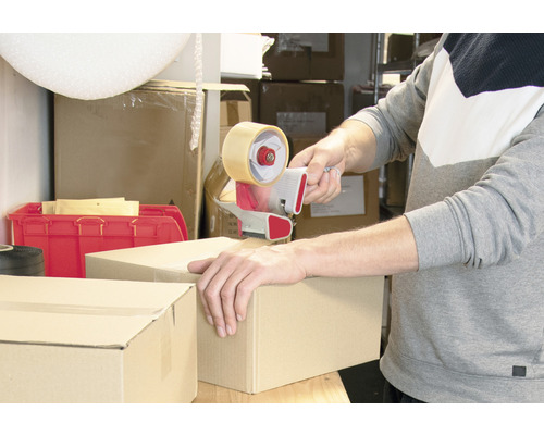 Eine Person verschließt einen Karton mit einem Handabroller.