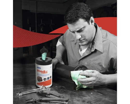 Ein Mann reinigt eine Oberfläche mit einem Wischtuch, neben ihm steht eine Spenderdose mit Wischtüchern der Marke Wypall.