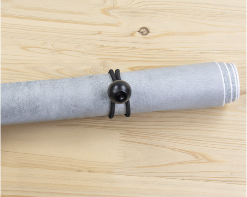 Gerollte Tapete mit Gummiband auf Holzgrund