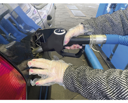 Eine Person in Handschuhen tankt Dieselkraftstoff in ein Auto.