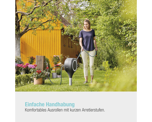 Frau benutzt eine Gartenschlauchbox im Garten.