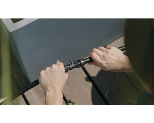 Eine Person verbindet einen Bewässerungsschlauch mit einem Verbinder.