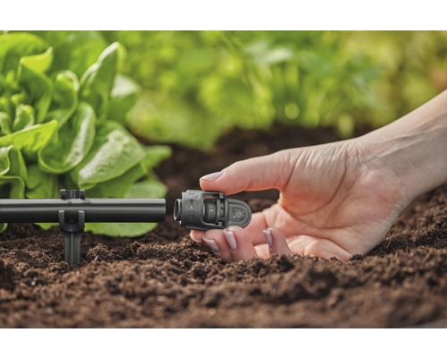 Detailaufnahme einer Person, die einen Verbinder an einem Bewässerungssystem im Garten befestigt