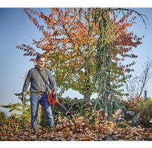 Mann benutzt einen Laubbläser zur Gartenarbeit.