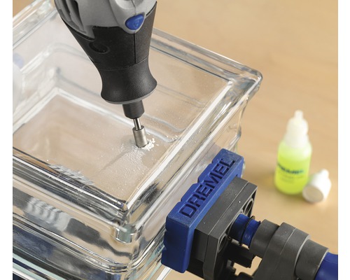 Dremel Multifunktionswerkzeug bohrt ein Loch in einen Glasbaustein, der mit einer Dremel Schraubzwinge fixiert ist