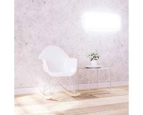 Szene mit Schaukelstuhl, Beistelltisch und Pflanze vor einer Wandleuchte