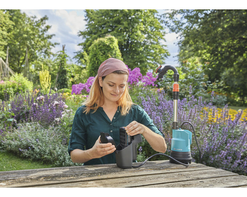 Frau montiert eine Gardena Schmutzwasserpumpe im Garten.