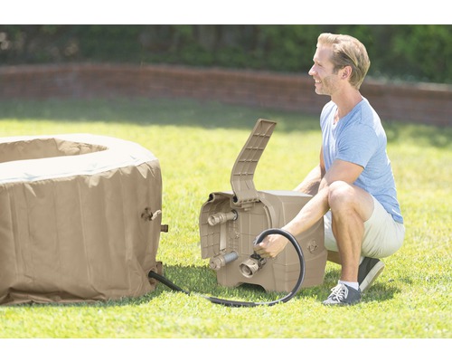 Mann schliesst eine tragbare Whirlpool-Pumpe an einen Whirlpool im Freien an.