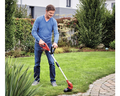 Mann verwendet einen Akku-Rasentrimmer im Garten.