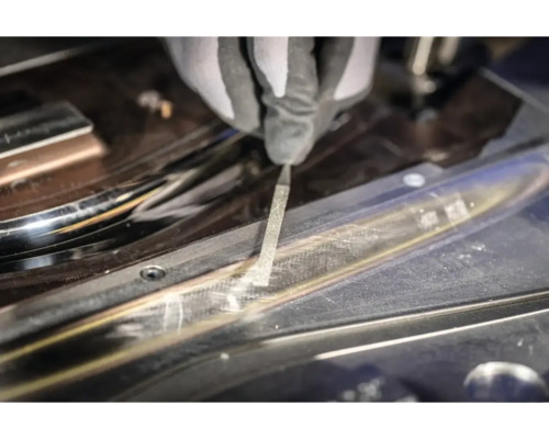 Eine Person bearbeitet eine Metalloberfläche mit einer Feile.