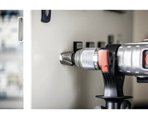 Eine Bohrmaschine mit Lochsäge bohrt ein Loch in eine Schalttafel.