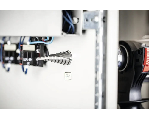 Metall Stufenbohrer vor weißem Schaltschrank