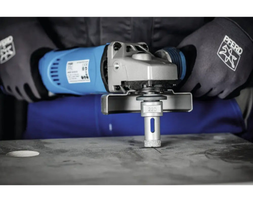 Eine Person bohrt mit einem Winkelschleifer und Diamantbohrer ein Loch in eine Platte.