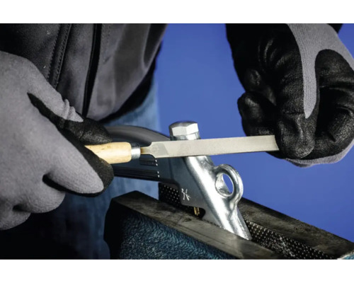 Eine Person feilt ein Metallteil, das in einem Schraubstock befestigt ist.