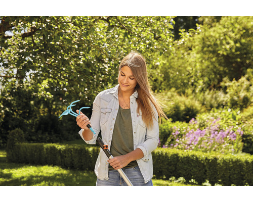 Frau hält einen Gartenkrallenaufsatz mit Stiel in einem Garten