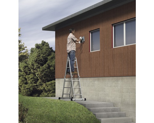 Mann arbeitet mit einer Schleifmaschine auf einer Leiter vor einem Haus.