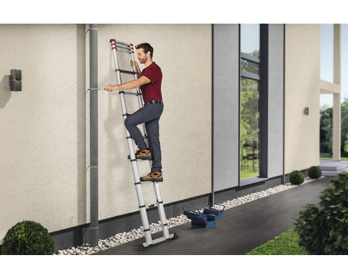 Mann auf einer Teleskopleiter bei Reparaturarbeiten an einem Haus.