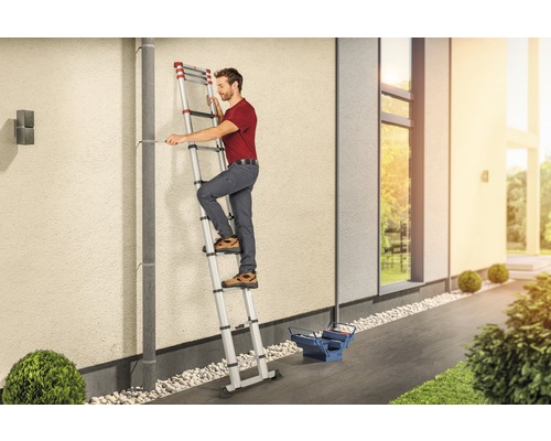 Mann auf einer ausziehbaren Leiter bei Reparaturarbeiten am Haus