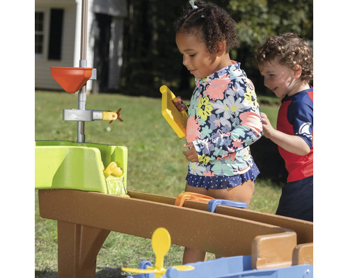 Kinder spielen mit einem Wasserbahnsystem im Freien.