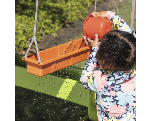 Kind spielt mit einer Wasserrinne im Freien
