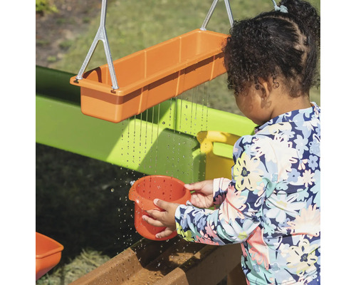 Kind spielt mit einer Wasserspielbahn im Garten