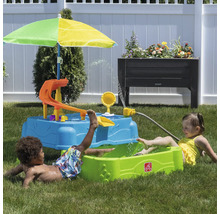 Spielszene im Garten mit Kinderspielplatz, Wasserspieltisch, Sonnenschirm und spielenden Kindern