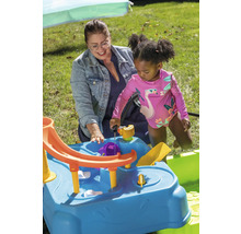 Mutter und Kind spielen mit einem blauen Wasserspieltisch im Garten.