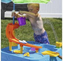 Kind spielt mit einem Wasserspieltisch im Freien, inklusive Eimer, Boot und Sonnenschirm