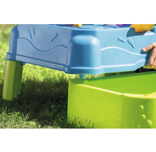 Detailansicht eines blauen und grünen Sand- und Wassertisches für Kinder auf einer Rasenfläche.