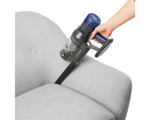 Eine Person reinigt ein graues Sofa mit einem Akku-Staubsauger.