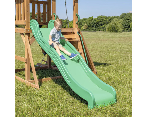 Junge rutscht auf einer grünen Rutsche eines Spielturms im Garten