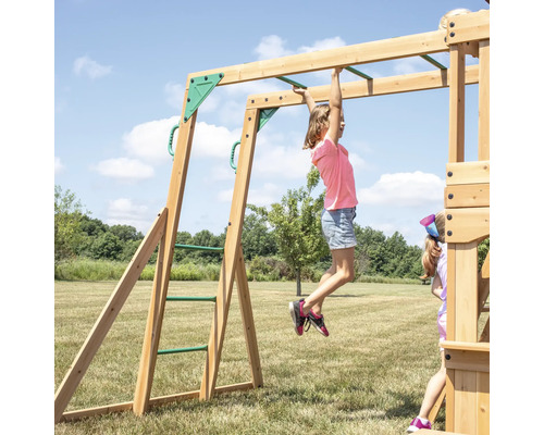 Kind hangt an einer Holzschaukel mit Sprossenleiter im Garten.