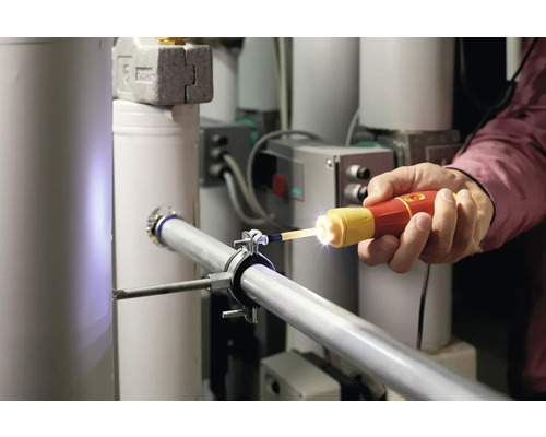 Eine Person verwendet eine Inspektionskamera an einer Rohrleitung in einem Gebäude.