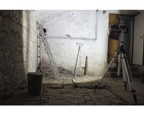 Kellerraum mit Leiter, Eimer, Farbroller und Baustrahler auf Stativ