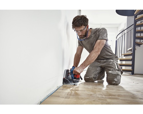 Mann schneidet Holzboden mit einer Tauchsäge.