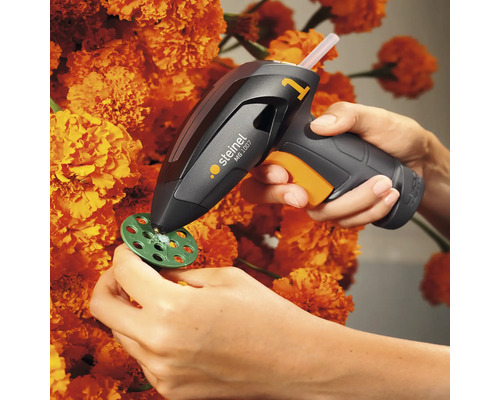 Heißklebepistole bei der Anwendung auf einem Bastelprojekt mit Blumen