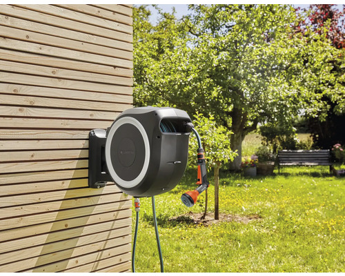 Gartenschlauchbox mit Schlauch und Spritze zur Gartenbewässerung an einer Holzwand montiert