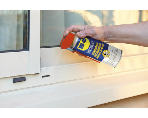 Eine Person sprüht Silikonspray von WD-40 auf ein Fenster