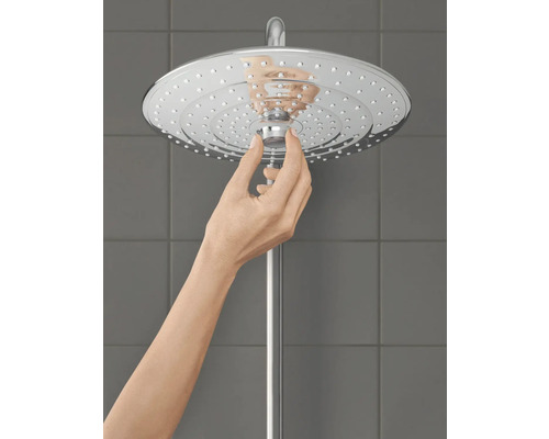 Eine Hand justiert einen Duschkopf aus Metall.