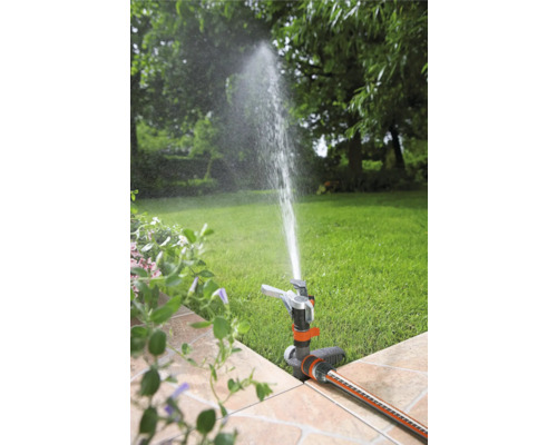 Gartenszene mit Rasensprenger bei der Bewässerung des Rasens