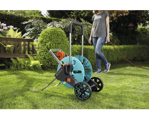 Gardena Schlauchwagen auf einer Rasenfläche mit einer Frau, die einen Schlauch hält.