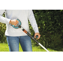 Person benutzt einen Unkrautstecher im Garten.