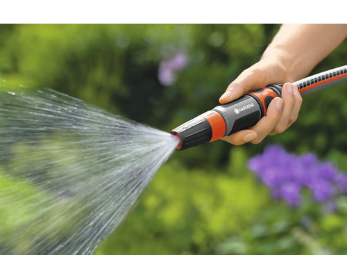 Eine Hand hält einen Gardena Gartenschlauch, aus dem Wasser spritzt.