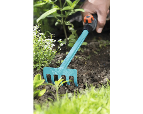 Gartenarbeit mit einem kleinen Rechen im Beet.