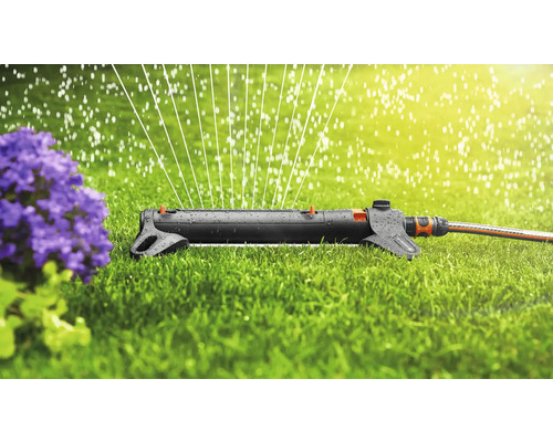 Rasensprenger beim Bewässern eines Rasens in der Nähe einer Pflanze